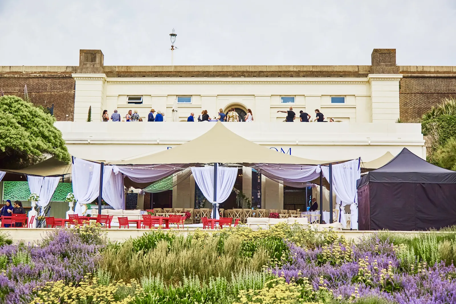 The Reading Room from the planting: guests on the upper terrace, white drapes over the tables below